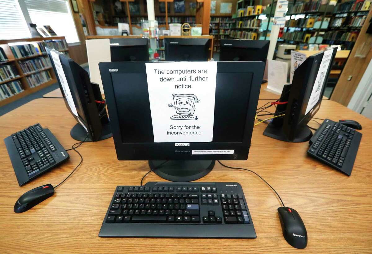 Signs on a bank of computers tell visitors that the machines are not working at the public library in Wilmer, Texas, Thursday, Aug. 22, 2019. Cyberattacks that recently crippled nearly two dozen Texas cities have put other local governments on guard. (AP Photo/Tony Gutierrez)