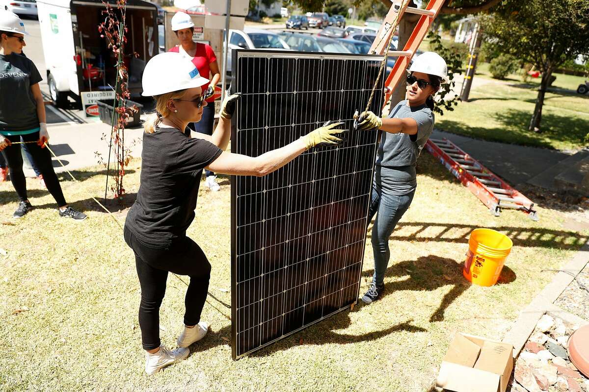 Katie Keyser and Virpal Sidhu prepare a solar panel for installation in Richmond, Calif., on Wednesday, September 11, 2019, as part of a non-profit venture to provide solar power to residential homes.