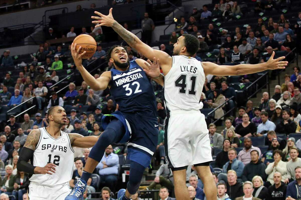 Minnesota Timberwolves' Karl-Anthony Towns , left, lays up as San Antonio Spurs' Trey Lyles defends in the second half of an NBA basketball game Wednesday, Nov 13, 2019, in Minneapolis. The Timberwolves won 129-114.