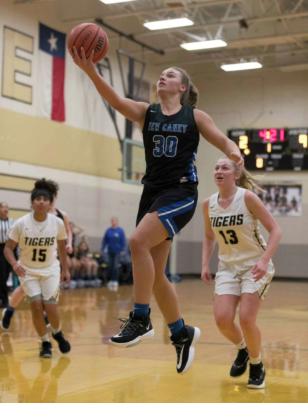 New Caney power forward Abigail Lynch (30) shoots a layup past Conroe guards Daniela Galindo (15) and Sarah Sowell (13) in the first quarter of a high school girls basketball game during the Lady Tiger Classic at Conroe High School, Thursday, Nov. 14, 2019, in Conroe.
