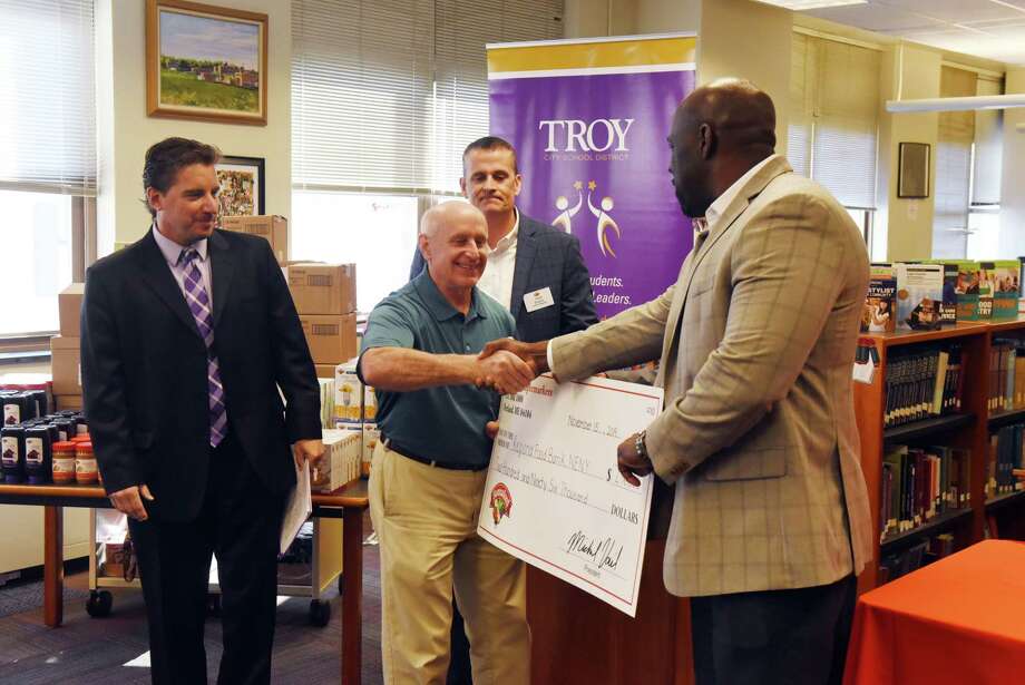 Mark Quandt, executive director of the Regional Food Bank of Northeast New York, center, shakes hands with Ean Rose, director of operations at Hannaford Supermarkets, right, during an announcement that Hannaford donated nearly $300,000 to establish food pantries in dozens of schools in New York on Friday, Nov. 15, 2019, at Troy High School in Troy N.Y. Troy is the first of 33 to open food pantries with help of grant money from Hannaford Supermarkets. (Will Waldron/Times Union) Photo: Will Waldron, Albany Times Union / 40048271A