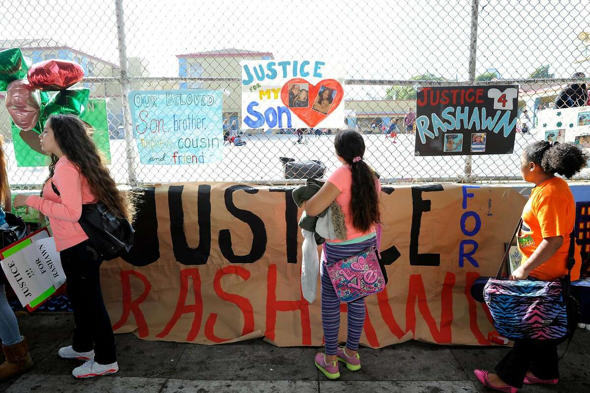 Students stop and look at the signs during a demonstration for Rashawn Williams, a 14-year-old student killed by a classmate, at Buena Vista Horace Mann School in San Francisco, CA, October 10, 2014. The family of Rashawn Williams, a 14-year-old honor roll student and football star who was killed by a classmate, is calling for the San Francisco district attorney to charge the 14-year-old boy accused of killing Rashawn as an adult.