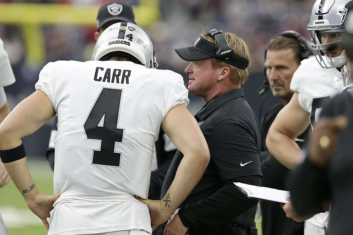 Oakland Raiders head coach Jon Gruden, center, talks with quarterback Derek Carr (4) during the first half of an NFL football game against the Houston Texans Sunday, Oct. 27, 2019, in Houston. (AP Photo/Michael Wyke)