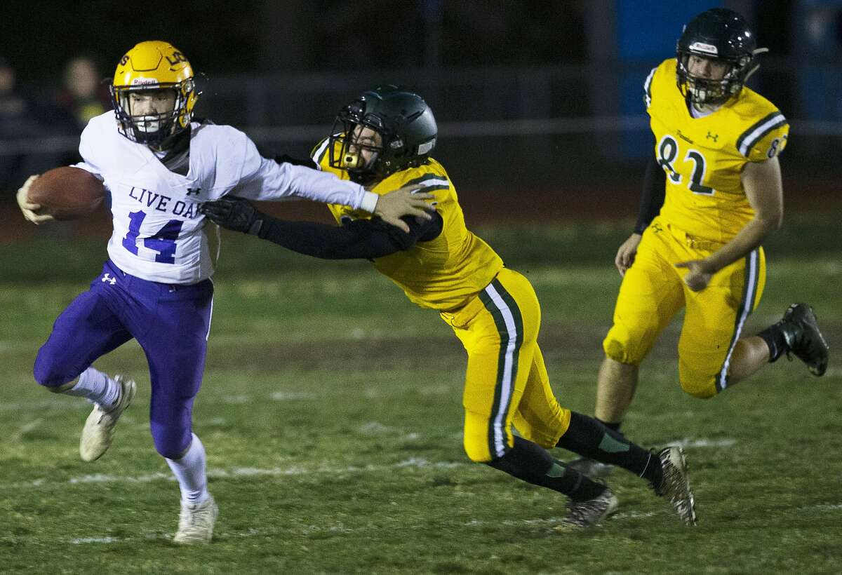 Live Oak High School quarterback Tony Vallejo, left, is chased down by Paradise High School's John Webster during the first half of a Northern California Division III playoff game in Paradise, Calif., Friday, Nov. 15, 2019.