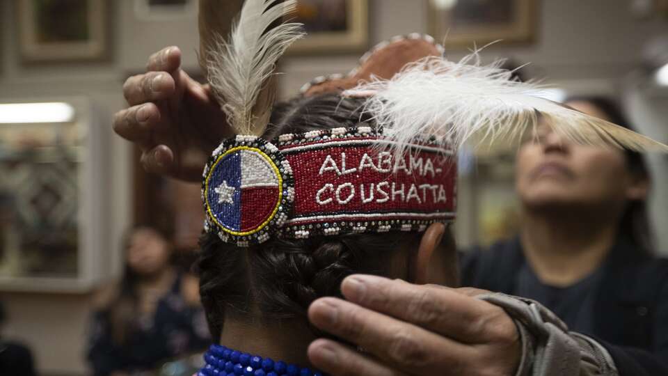 Bianka Gardner, left, gets some help from Marisa Williams placing a feather into her headband as members of the Alabama-Coushatta perform dances and talk about the tribeâs history at the Heritage Museum of Montgomery County, Saturday, Nov. 16 2019, in Conroe.