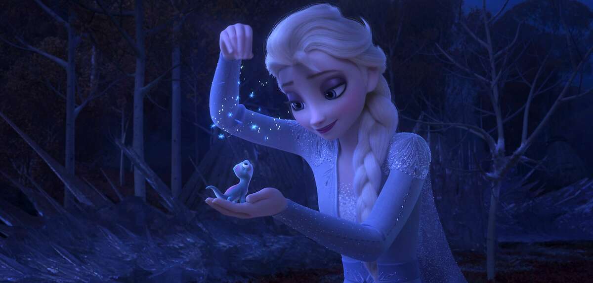 This image released by Disney shows Elsa, voiced by Idina Menzel, sprinkling snowflakes on a salamander named Bruni in a scene from "Frozen 2." (Disney via AP)