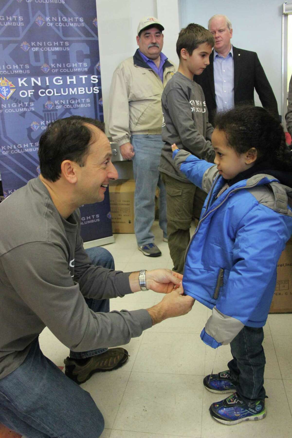 Anthony Minopoli, Knights of Columbus chief investment officer, helps a child with a new winter coat at the 5th annual Day of Joy event Saturday in New Haven.