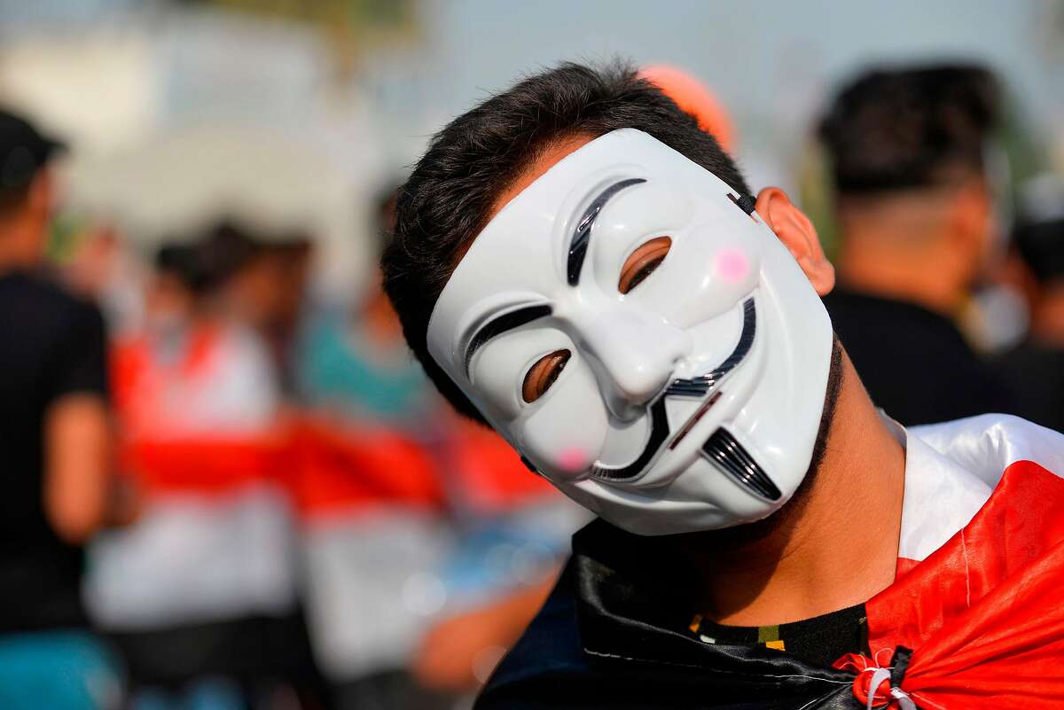 An Iraqi protester wearing a Guy Fawkes mask takes part in ongoing anti-government demonstrations in the eastern city of Diwaniyah on November 3, 2019. - Protesters in Iraq's capital and the country's south shut down streets and government offices in a new campaign of civil disobedience Sunday, escalating their month-long movement demanding change to the political system.