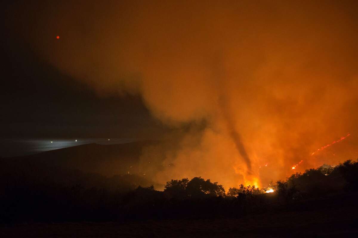 A fire whirl, or fire tornado, rises from advancing flames as the moon (L) is reflected in the ocean in the early morning hours of June 18, 2016 at the Sherpa Fire near Santa Barbara,California. / AFP / DAVID MCNEW (Photo credit should read DAVID MCNEW/AFP/Getty Images)
