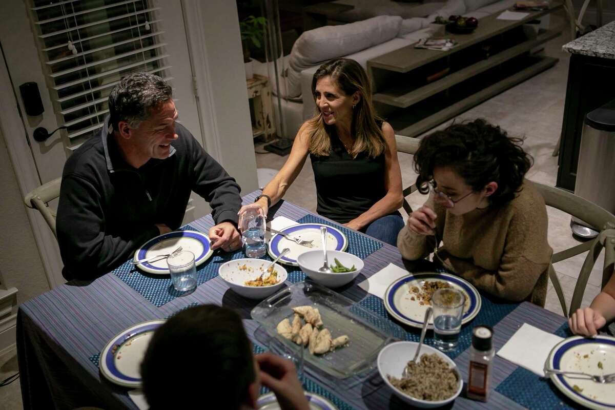 Nusha Bladinieres talks to her husband Jan Michell as they eat dinner with Nusha's children in their home in New Braunfels.