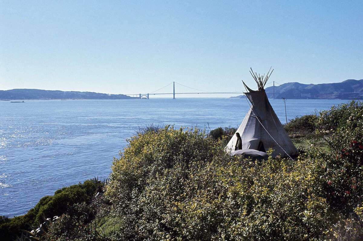 FILE - In this Nov. 18, 1970, file photo, Sioux Indian John Trudell stands next to the teepee he set up for himself during the Native American occupation of Alcatraz Island. The week of Nov. 18, 2019, marks 50 years since the beginning of a months-long Native American occupation at Alcatraz Island in the San Francisco Bay. The demonstration by dozens of tribal members had lasting effects for tribes, raising awareness of life on and off reservations, galvanizing activists and spurring a shift in federal policy toward self-determination. (AP Photo/File)
