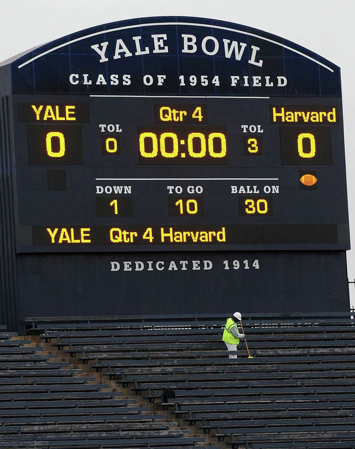 A worker cleans under the scoreboard at Yale Bowl as contractors and Yale employees ready the stadium for the big match-up against Harvard in 2011.