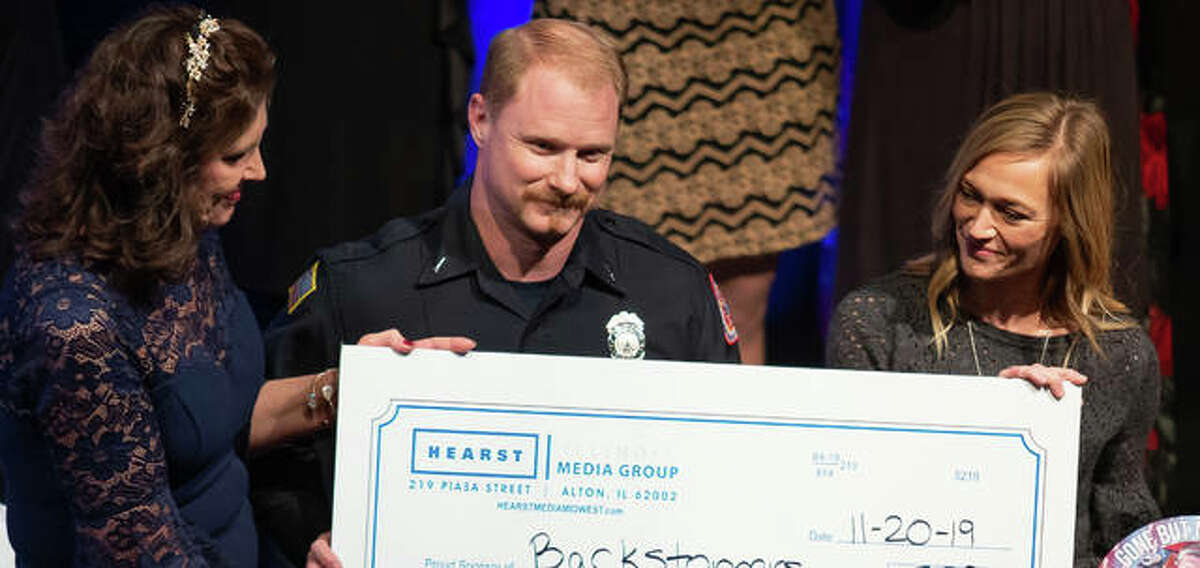 Godfrey Fire Department Lieutenant and EMT Chris Dennison (center) and Allison Ringering (right), the widow of Godfrey Fire Capt. Jake Ringering, who was killed while fighting a house fire in March, accept a donation to Backstoppers from Telegraph and Intelligencer publisher Denise Vonder Haar (left) Wednesday night during the newspapers’ annual Best of the Best of Madison County and the Riverbend held the Hathaway Cultural Center on the campus of Lewis and Clark Community College. Jake Ringering was honored as firefighter of the year at the ceremony. Dennison gave a heartfelt address to the audience of nearly 600, thanking area citizens for the support provided to his department and the Ringering family since the beloved captain’s death.