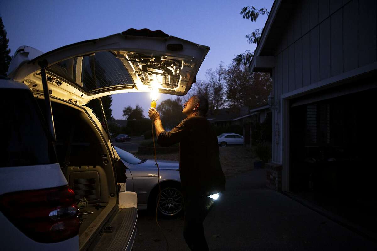 William Douglas Hitt outside his home fixes his power window before driving to his upholstery class on Wednesday, Nov. 20, 2019, in St. Helena, Calif. The power is out at his neighborhood off of Spring Street. Hitt is using a generator to power his light. PG&E has shut off the power to more than 40,000 homes in an effort to prevent wildland fires.