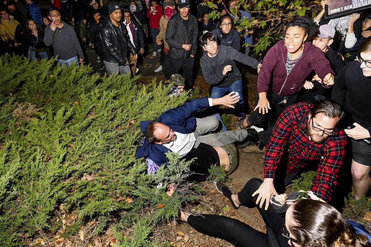 A man leaving a speech by conservative commentator Ann Coulter falls to the ground after being pushed by protesters at the University of California, Berkeley, Wednesday, Nov. 20, 2019, in Berkeley, Calif. Hundreds of demonstrators gathered as Coulter delivered a talk titled "Adios, America!" (AP Photo/Noah Berger)