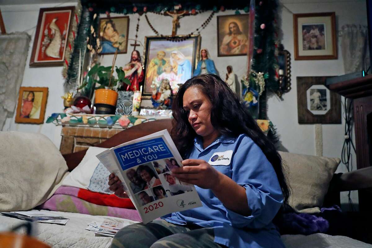 While going through the mail, LSG Sky Chefs' employee Melieni Cruz looks through her mother's Medicare brochure at her home in Oakland, Calif., on Monday, November 18, 2019.