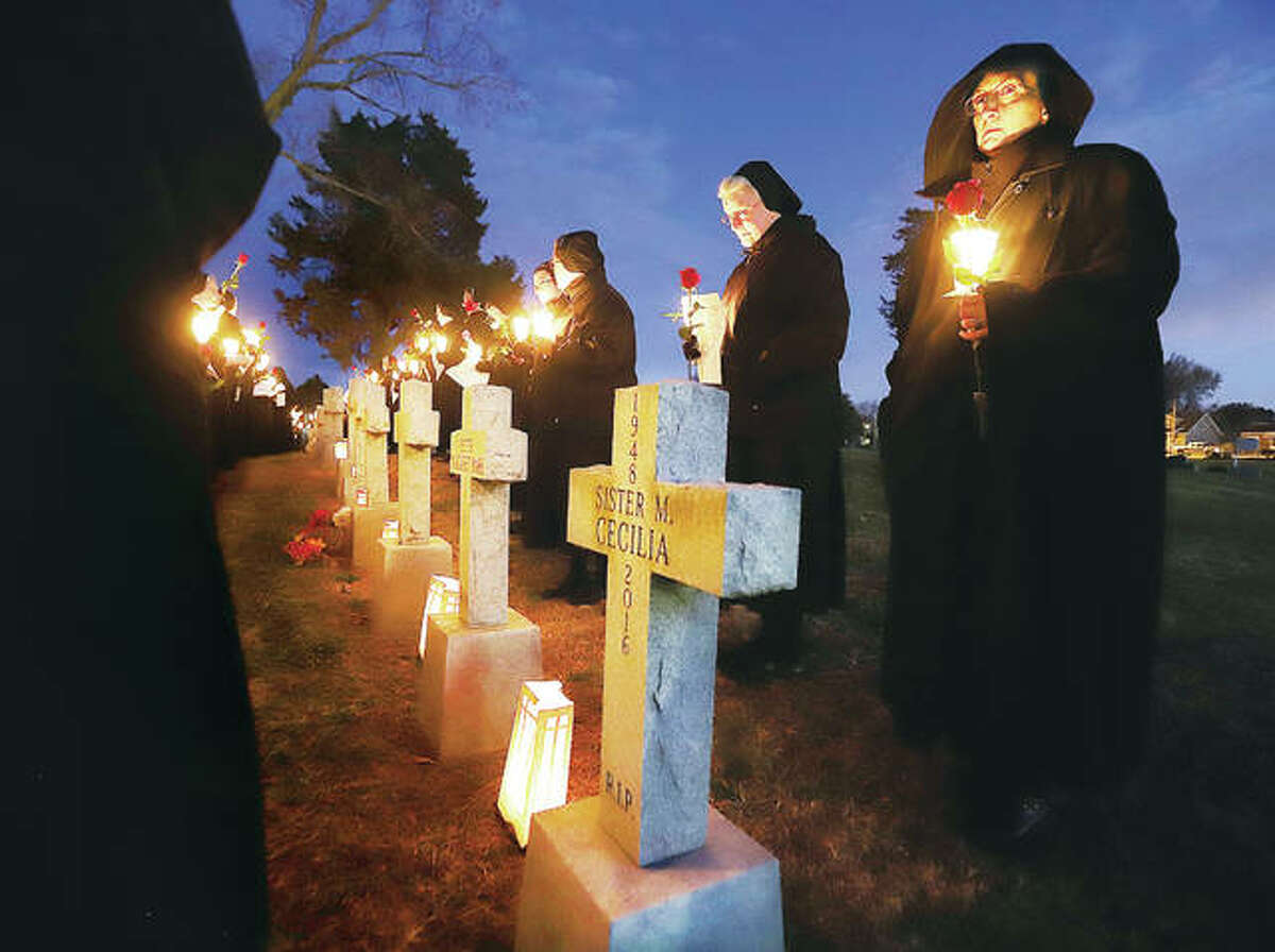 Sisters stand in front of the graves of nuns from the Sisters of St. Francis of the Martyr St. George in Alton Friday evening to lay roses on the graves as part of a celebration of the order’s 150th year. Founded in 1869, the group’s American Province began in St. Louis in 1923 before moving to Alton two years later.