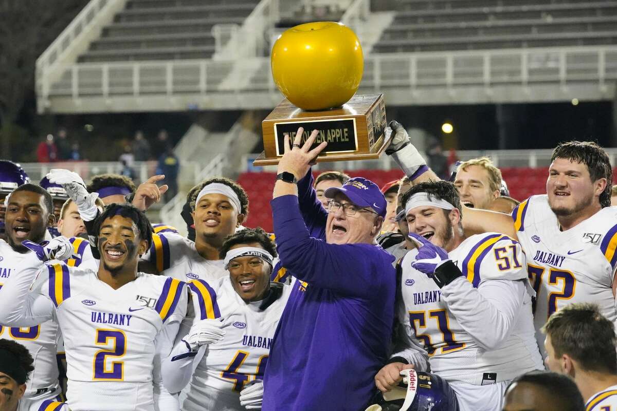 UAlbany coach Greg Gattuso and his players celebrate with the Golden Apple trophy after their 31-26 victory at Stony Brook on Saturday, Nov. 23, 2019. (Gregory A. Shemitz / Special to the Times Union)