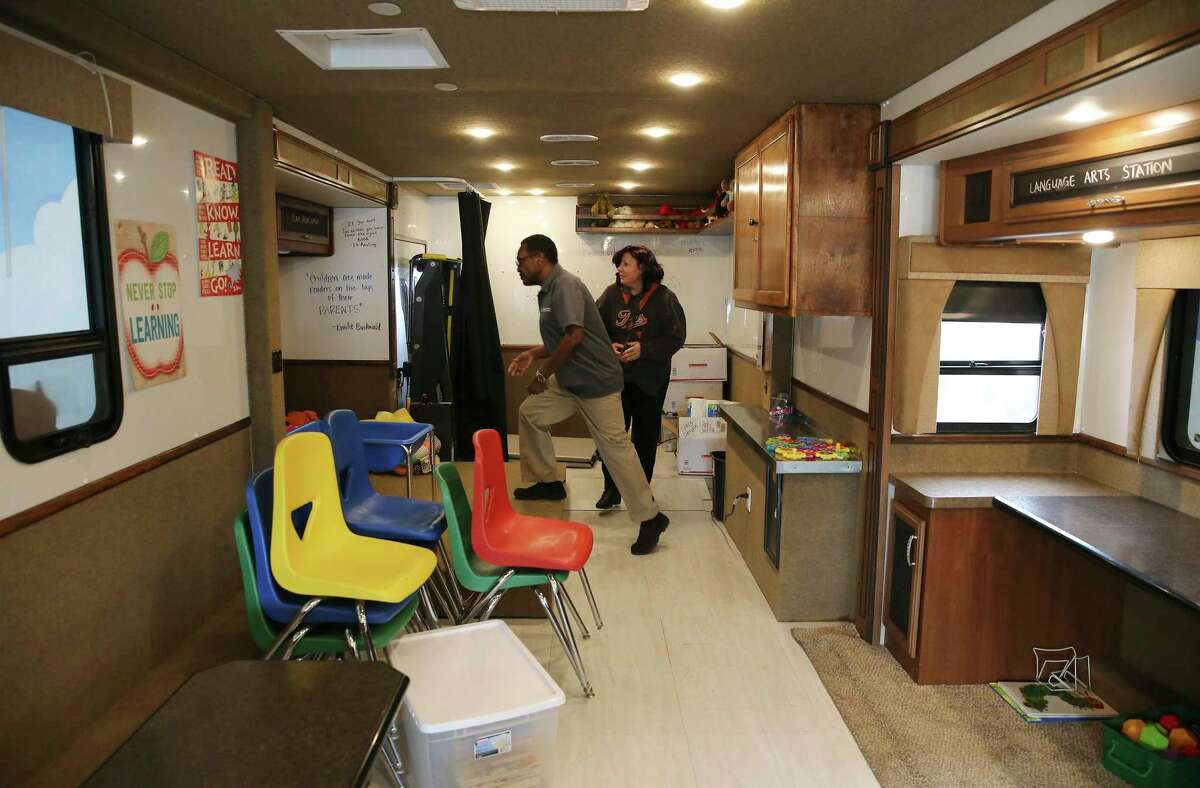 James Stewart (center) and Angela Bunting set up the interior of the Literacy Caravan before a visit by school children while visiting Camelot Elementary on Friday, Oct. 11, 2019. At each stop Stewart sets up the RV which is equipped with educational toys and activities. Students can play in the RV before they're handed a free book of their choice on the way out.