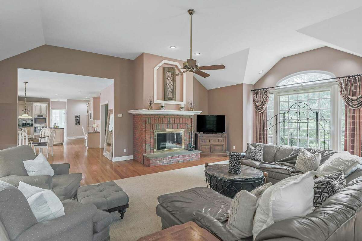 The family room features a tall vaulted ceiling, red brick fireplace, and a large multi-paned window.