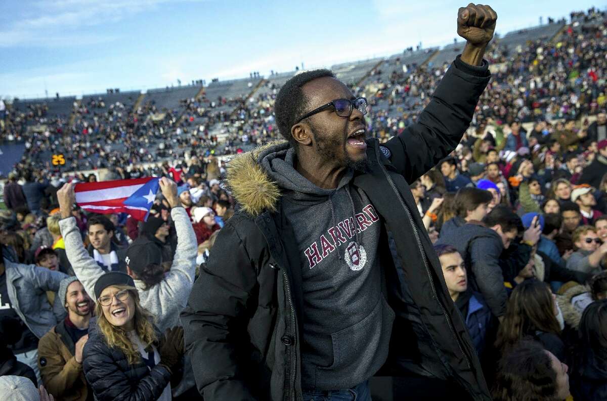 In this Saturday, Nov. 23, 2019, photo, Harvard and Yale students protest during halftime of the NCAA college football game between Harvard and Yale at the Yale Bowl in New Haven, Conn. Officials say 42 people were charged with disorderly conduct after the protest interrupted the game. (Nic Antaya/The Boston Globe via AP)
