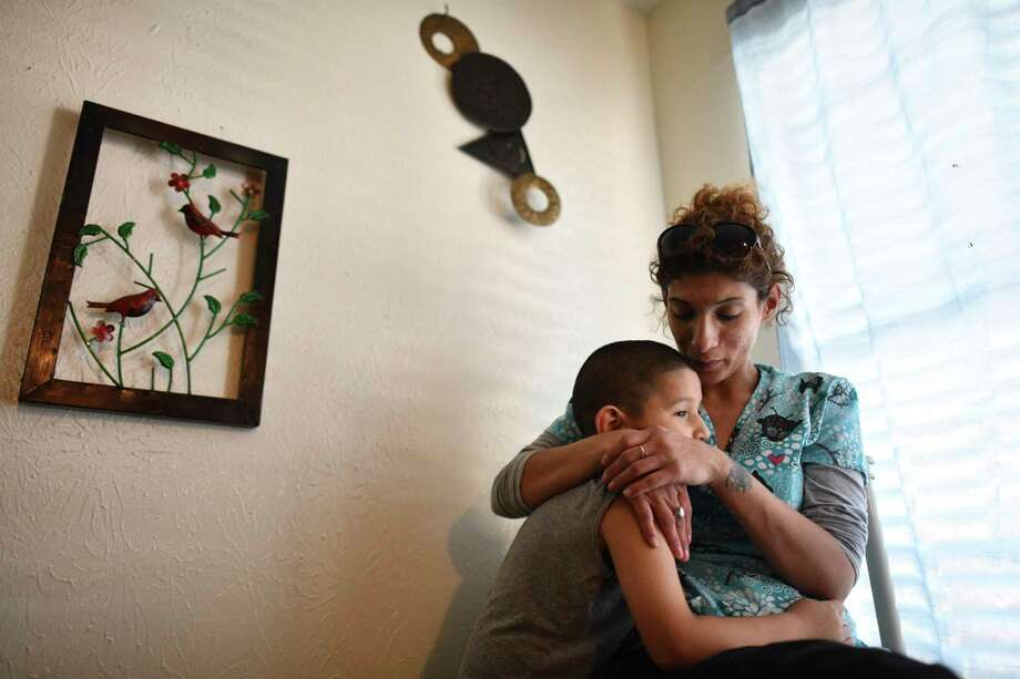 Rebecca Perez holds her son Leroy Gomez, now 7, in their apartment before they were evicted. She and her two boys now live with her father. Photo: Billy Calzada / San Antonio Express-News