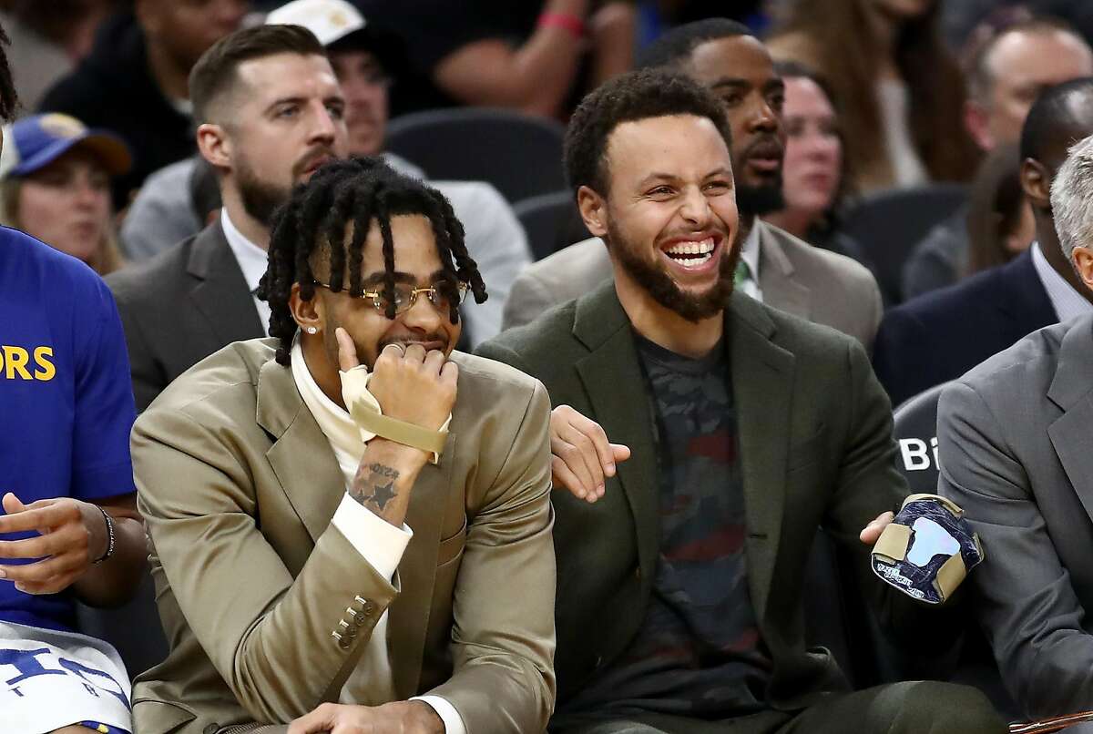 SAN FRANCISCO, CALIFORNIA - NOVEMBER 25: Injured players D'Angelo Russell #0 (left) and Stephen Curry #30 of the Golden State Warriors react on the bench during their game against the Oklahoma City Thunder at Chase Center on November 25, 2019 in San Francisco, California. NOTE TO USER: User expressly acknowledges and agrees that, by downloading and or using this photograph, User is consenting to the terms and conditions of the Getty Images License Agreement. (Photo by Ezra Shaw/Getty Images)