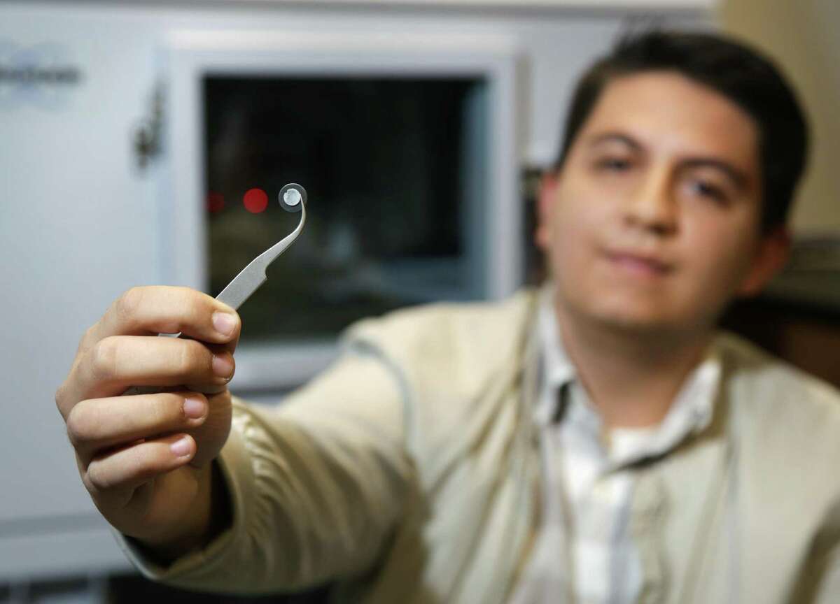 UTSA graduate student Joel Gomez holds a human bone sample in front of the machine that scans and analyzes its make-up.