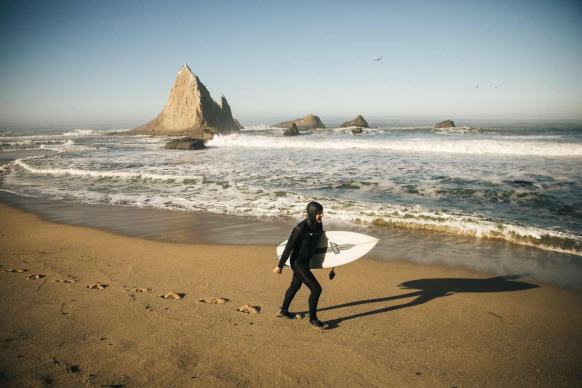 Jameson Kenway walks on Martins Beach for a morning surf in Half Moon Bay, Calif. Thursday, October 26, 2017.