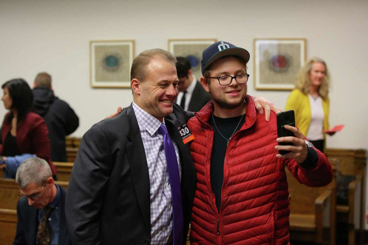 Tim Eyman, left, takes a selfie with a fan during a break in a hearing where a coalition of counties, transportation agencies and the city of Seattle argued in front of a King County Superior Court judge for a motion to block Eyman's Initiative 976 from taking effect Dec. 5, saying there would be irreparable harm, that it was unconstitutional and violated the single-subject rule, Tuesday, Nov. 26, 2019.