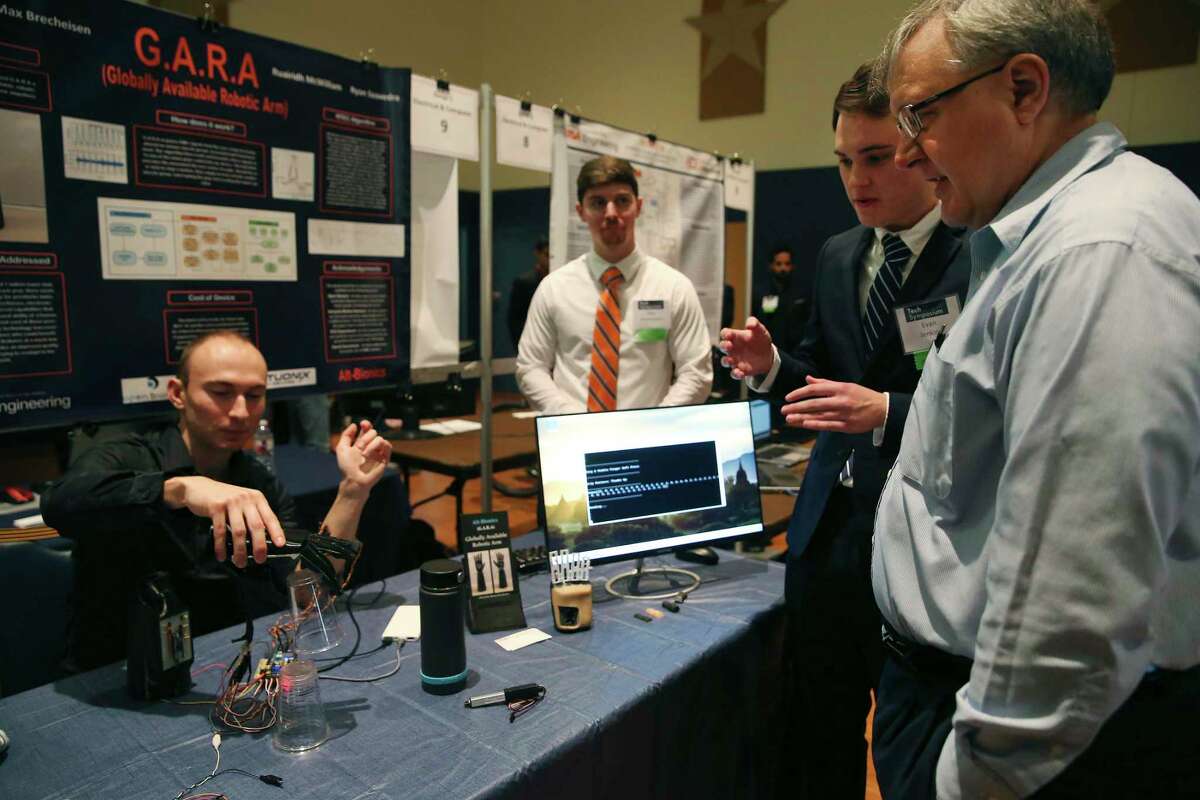 Electrical and computer engineering professor Lars Hansen, right, listens as, from left, Ryan Saavedra, Max Brecheisen and Evan Jenkins explain their Globally Available Robotic Arm at the University of Texas at San Antonio Fall 2019 Tech Symposium on Tuesday. They and fellow student Ruairidh McWilliam designed and built the low-cost bionic hand for below-elbow amputees.