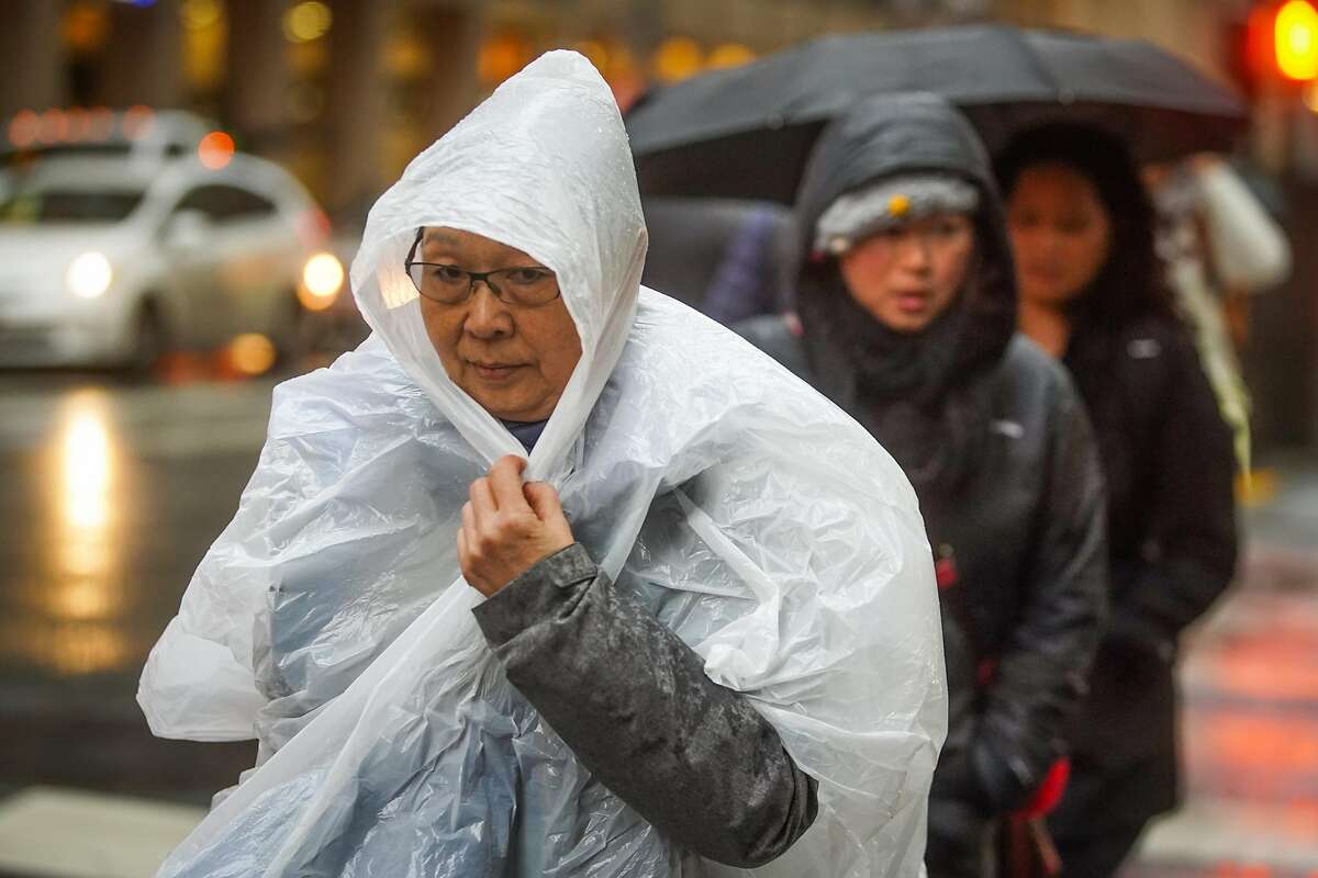 People take cover as they cross Sutter Street during a rainstorm in the Financial District in San Francisco, California, on Tuesday, Nov. 26, 2019.