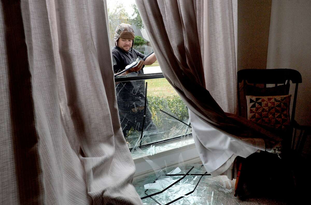 Adrian Torres pulls shards of glass from a window frame as he comes to board up the multiple broken windows at the home of Wilma and C. V. Shahan in Port Neches following Wednesday morning's explosion at the TPC plant. Photo taken Wednesday, November 27, 2019 Kim Brent/The Enterprise