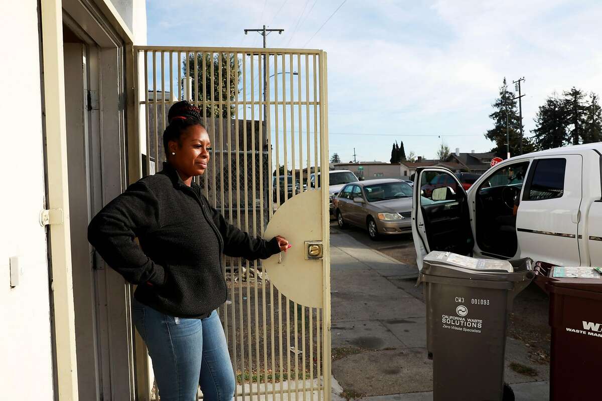 Tashawna Harris stands by the door of her apartment in Oakland, Calif., on Saturday, November 16, 2019. A year ago, Harris, who was working security at an East Oakland business, walked across the street to knock on doors for help after her car wouldn't start. Robert Waggener offered jumper cables. He continues to help her to get her life going in the right direction.