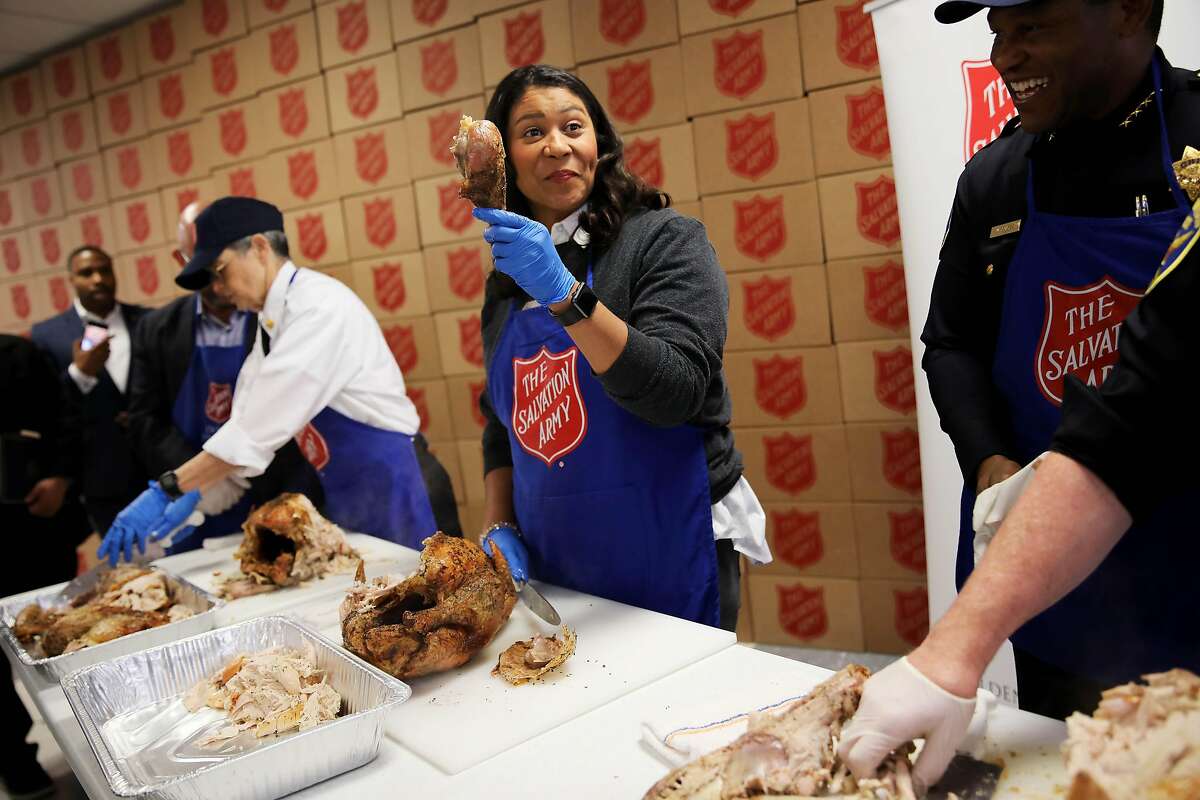 Flanked between San Francisco Fire Chief Jeanine Nicholson, left, and San Francisco Chief of Police William Scott, right, San Francisco Mayor London Breed holds a turkey leg as she asks if she should cut the meat off of it during Salvation Army's annual turkey carving event in San Francisco, Calif., on Wednesday, November 27, 2019. Approximately 1,600 pounds of turkey was carved up to serve in various Salvation Army Thanksgiving Day dinner events on Thursday. "We know that it is a blessing be a blessing to others and that's what San Francisco does best," Breed said. "When people need us, we roll up our sleeves, we come together and we make magic happen."