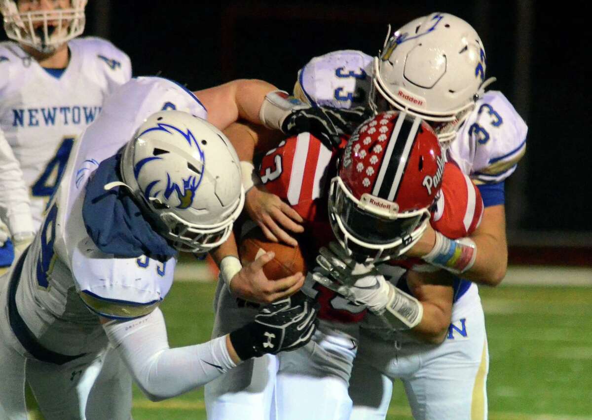 Newtown's James Knox (99), left, and teammate Jared Dunn (33) tackle Masuk QB Nicholas Saccu during football action in Monroe, Conn., on Wednesday Nov. 27, 2019.