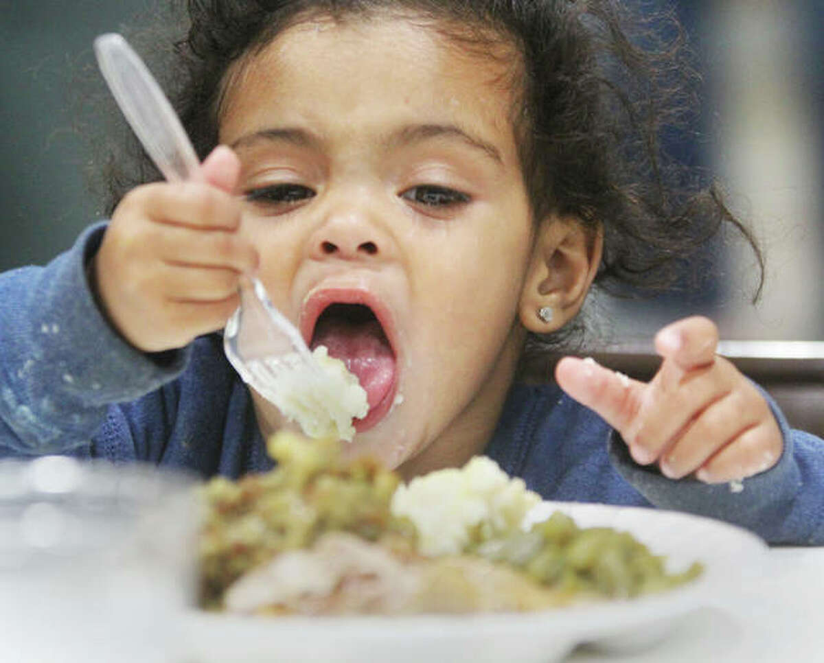 Alaejiah West, 2, works on eating mashed potatoes Wednesday during a Thanksgiving dinner put on by Abundant Life Community Church at the Salvation Army in Alton. The church has been providing the dinner for about 15 years.