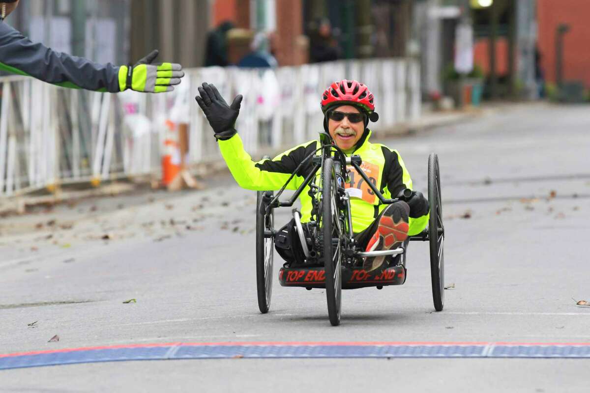 Patrick Glover of Clifton Park crosses the finish line during the Troy Turkey Trot 10K race on Thursday, Nov. 28, 2019, in Troy, N.Y. Glover, who had won the race back in early 80s, was unable to run and so was allowed to use the hand-powered bike on the course. (Paul Buckowski/Times Union)