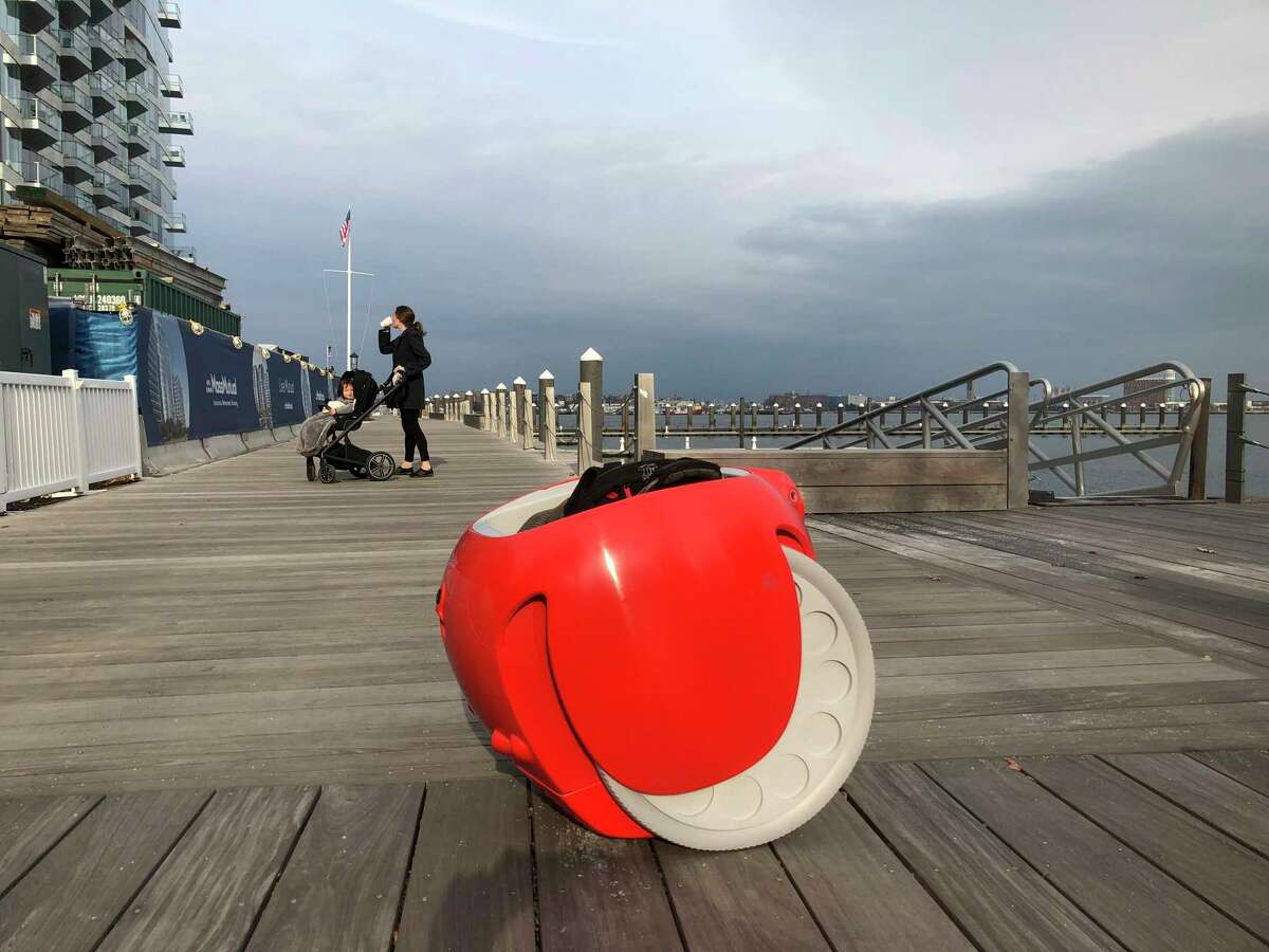 A cargo-carrying robot called the Gita sits near a waterfront park on Monday, Nov. 11, 2019, in Boston. A subsidiary of Italian automaker Piaggio designed the machine to follow its owner carrying groceries and other items. (AP Photo/Matt O'Brien)