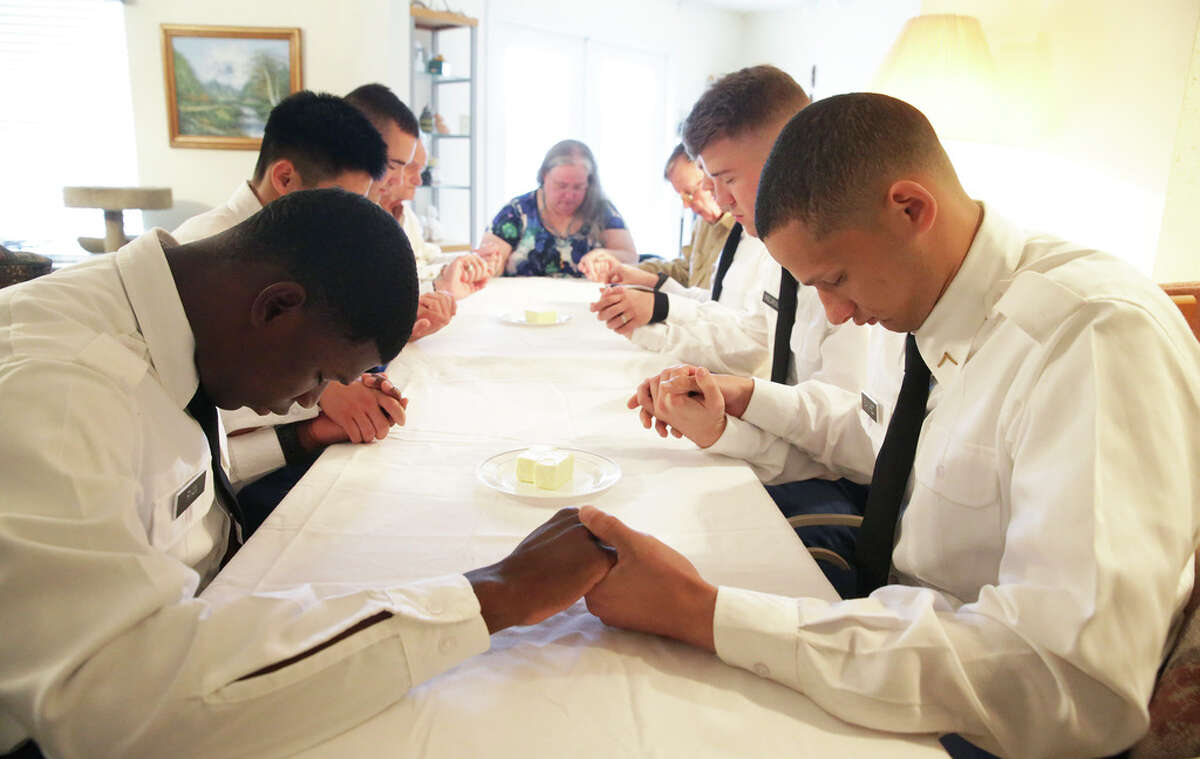 Pvt. Ryan Wooshalno, left, and Pvt. George Sanchez join with the group in offering a blessing as Jan and Travis Briggs hosts soldiers from Ft. Sam Houston at her home for Thanksgiving dinner on Nov. 28, 2019.
