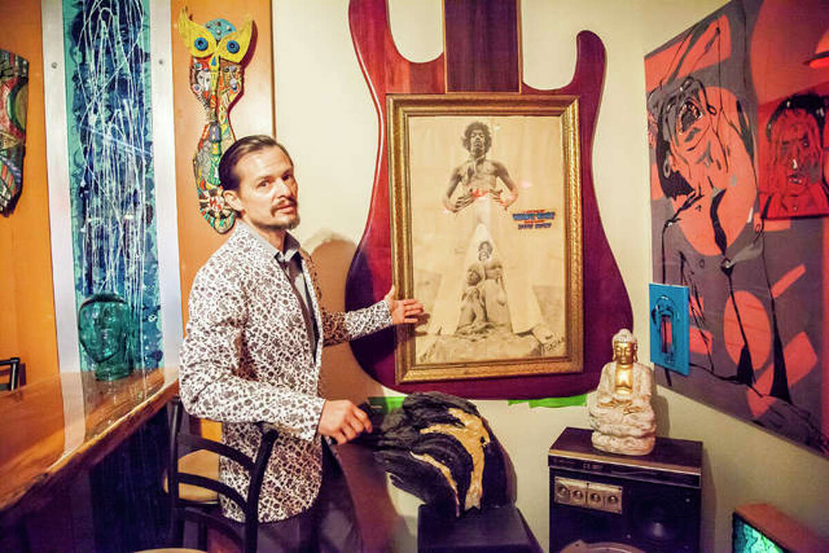 Artist Michael Snider at his home in Alton, standing next his single greatest possession, a 1967 Jimi Hendrix poster signed by photographer Ron Raffaelli.
