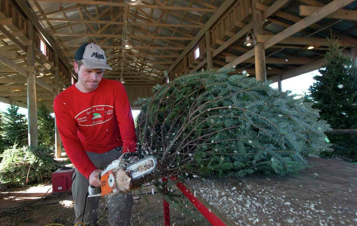 Brendan Mack trims the base of a Christmas tree for customer at Spring Creek Growers in 2017 in Magnolia.
