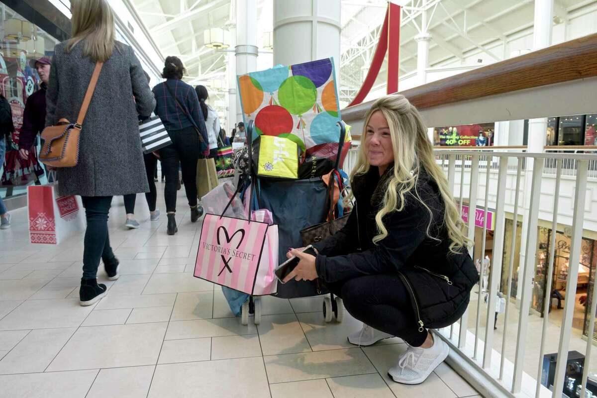 Rosalie Passiatore, of Ossining, NY, stopped to check her phone while Black Friday shopping at the Danbury Fair mall. Passiatore has a yearly tradition of shopping with her mother, two sisters and an aunt on black Friday, they ever have special t-shirts they wear. Thursday, November 29, 2019, in Danbury, Conn. Passiatore and family got to the mall at 5:30 AM to shop.