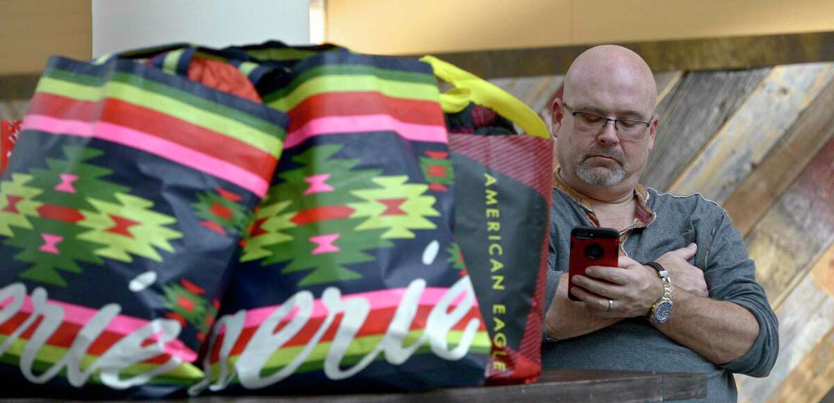 Paul Sherman, of Poughkeepsie, NY, checks his phone while keeping an eye on some shopping bags during Black Friday at the Danbury Fair mall. Sherman, who got to the mall at 5:30 AM with his wife to shop said,