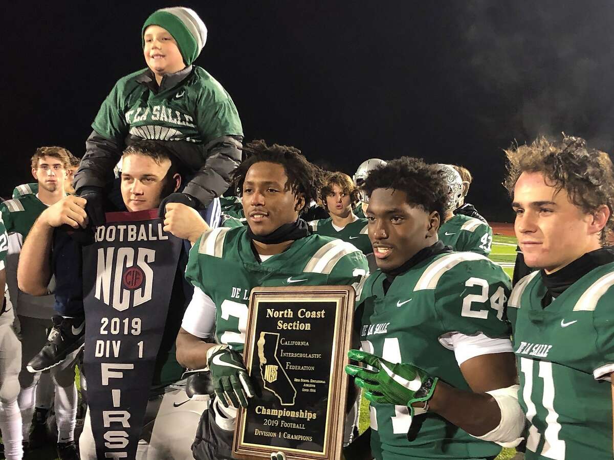 From left to right, De La Salle senior captains Ben Roe, James Coby, Shamar Garrett and Vince Bianchina pose with the NCS Division I championship banner and plaque.