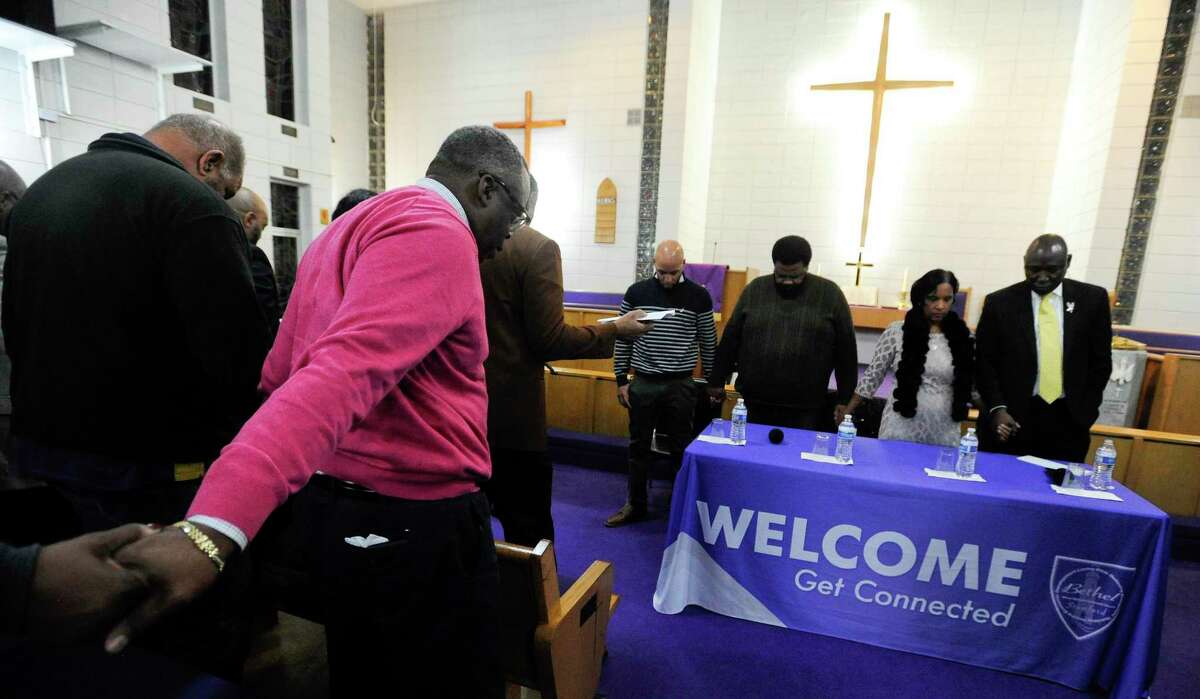 Attendees join in prayer, along with attorney Benjamin Crump, at right, holding hands Valerie Jaddo and Steven Barrier Sr. at the start of a Community Rally for Justice at Bethel A.M.E. Church in Stamford on Tuesday.