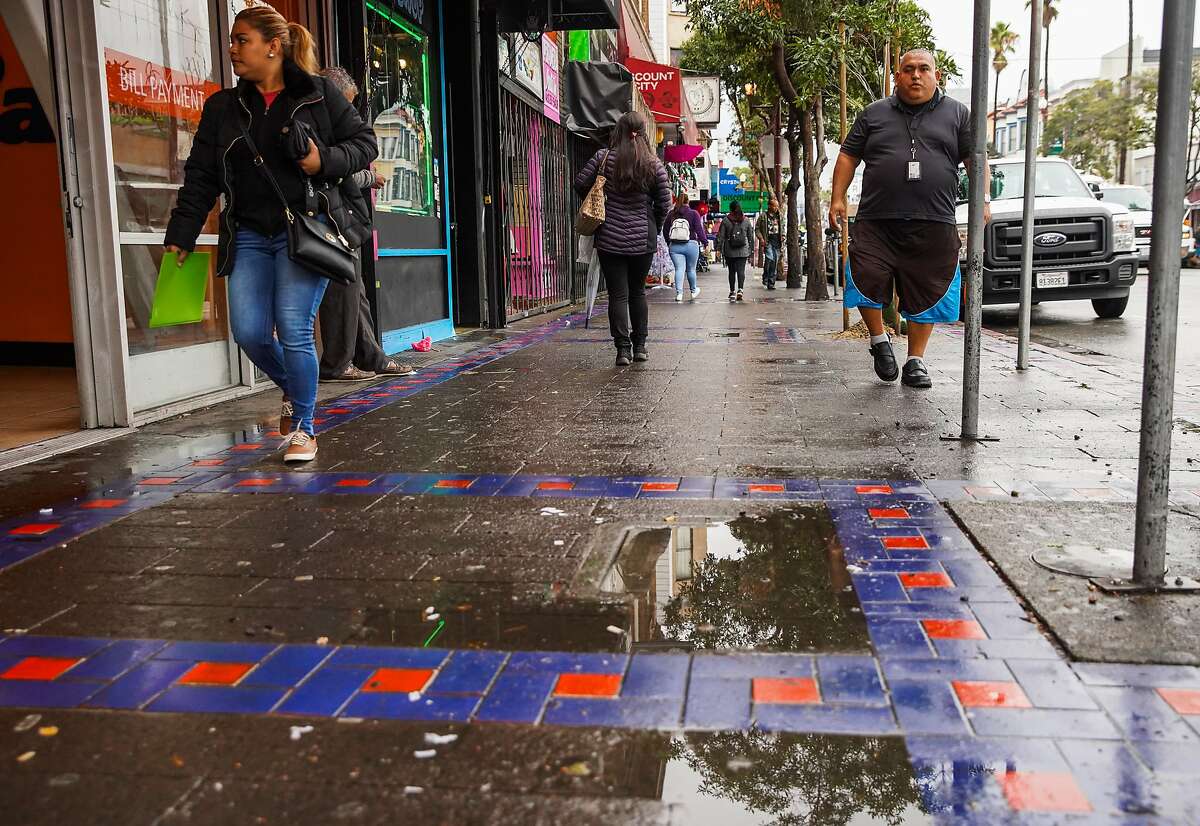 People walk on Mission Street after heavy rains in San Francisco, California, on Monday, Dec. 2, 2019.