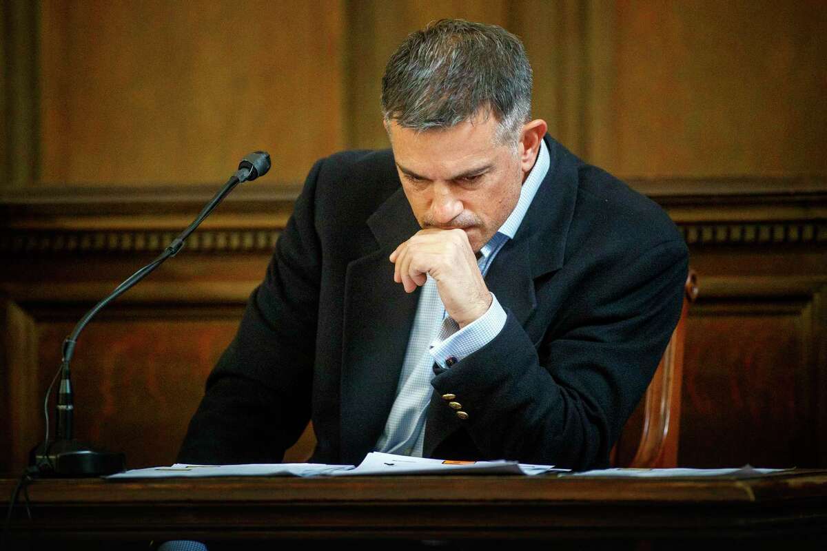 Fotis Dulos examines a financial document presented by his attorney William Murray during testimony in a civil case in Hartford Superior Court during his testimony in a civil case Wednesday, Dec. 4, 2019, in Hartford, Conn.