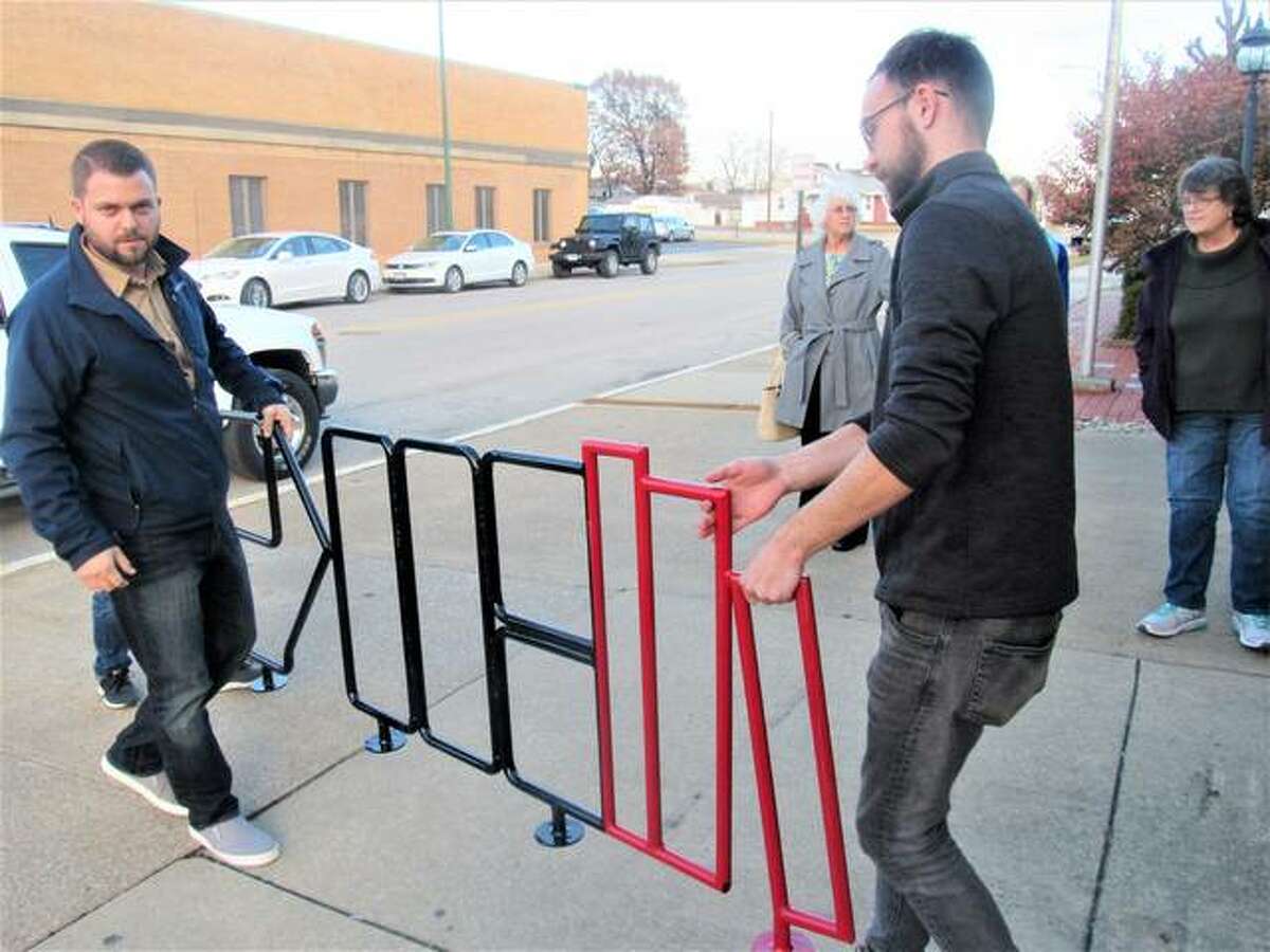 Wood River Library Foundation member Andy Russell and Stock Auto Body and Mechanical employee Dylan Eberhart transfer a new bike rack to the Wood River Public Library.
