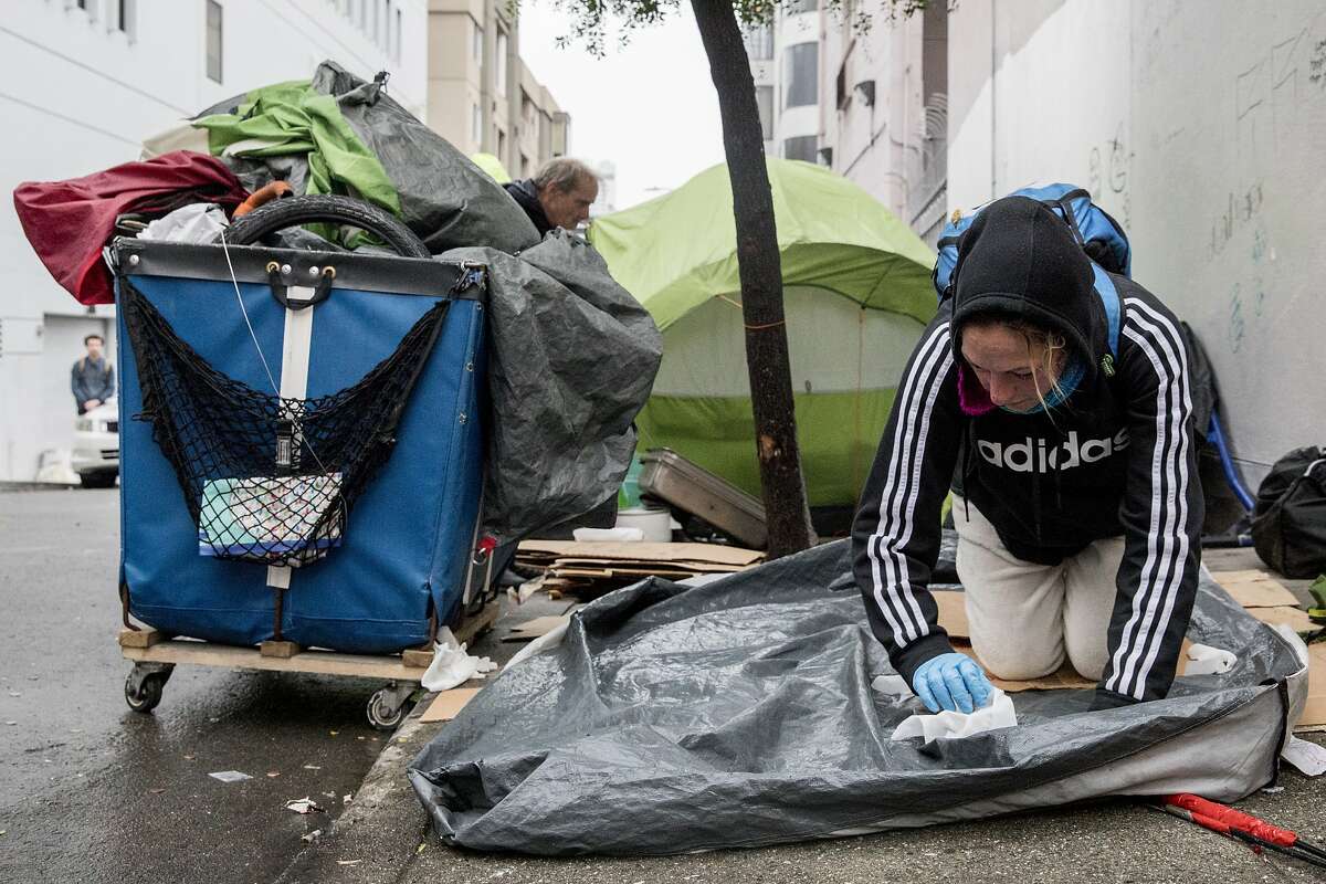 Bonnie Lukesh works to clean off her tent before packing it up with her other belongings during a sweep of homeless tents and encampments by the Department of Public Works and San Francisco Police along Willow Street in San Francisco, Calif. Wednesday, Dec. 4, 2019.